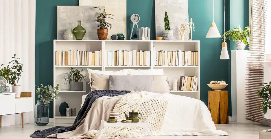 Naturalist bedroom with a white and green palette and a large bookcase filled with books serving as a headboard